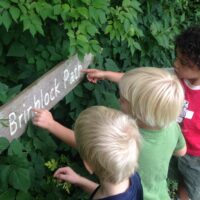 kids pointing at a park sign