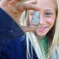 Child holding flint arrowhead.